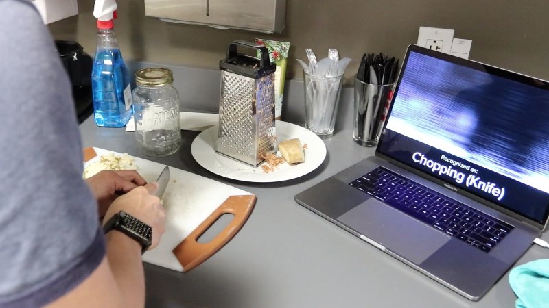A student tests the Carnegie Mellon smartwatch that detects hand motion activity and the smartwatch detects chopping a vegetable.
